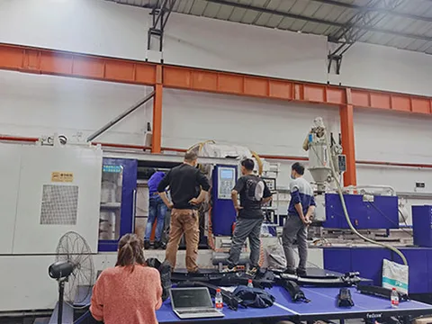 People reviewing an injection molding work area in an image from the Dongguan New Oriental source site's About section